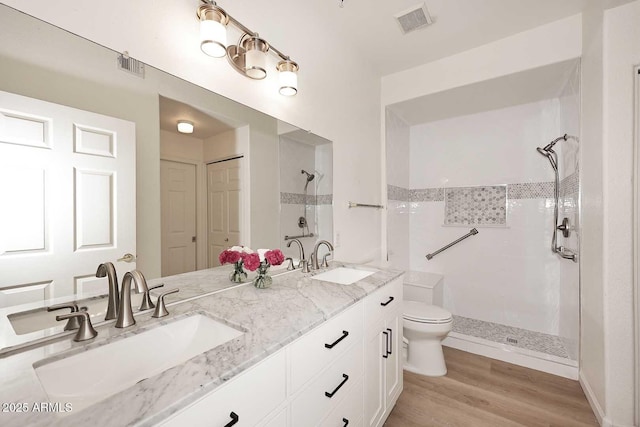 full bath with toilet, visible vents, a sink, and tiled shower