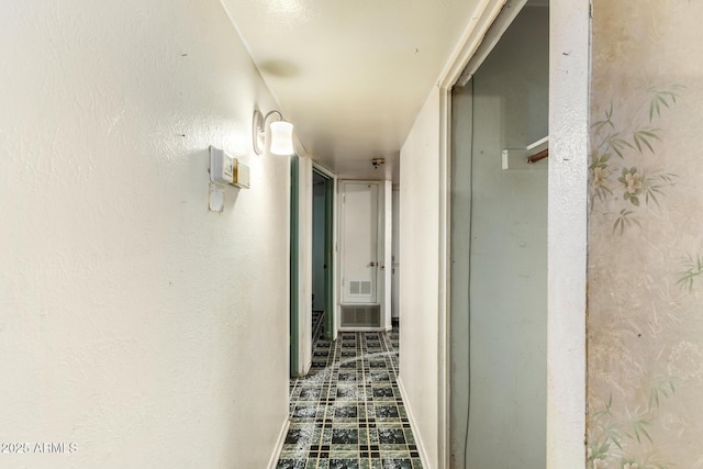 corridor with tile patterned floors, visible vents, and baseboards