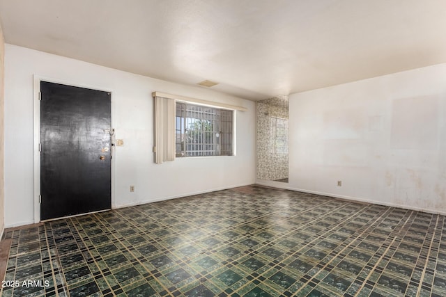 unfurnished room featuring tile patterned floors, visible vents, and baseboards