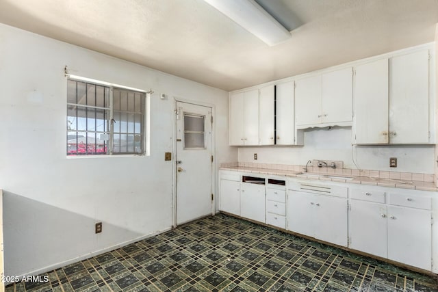 kitchen featuring tile countertops, white cabinets, dark floors, and a sink