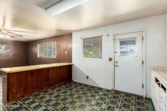 foyer with tile patterned floors, wood walls, and ceiling fan