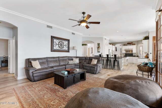 kitchen featuring appliances with stainless steel finishes, white cabinetry, ornamental molding, a kitchen island, and light hardwood / wood-style floors