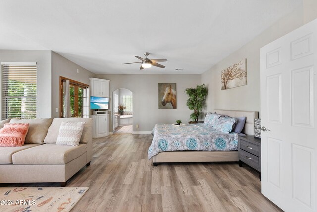 bedroom featuring ceiling fan, light hardwood / wood-style floors, and connected bathroom