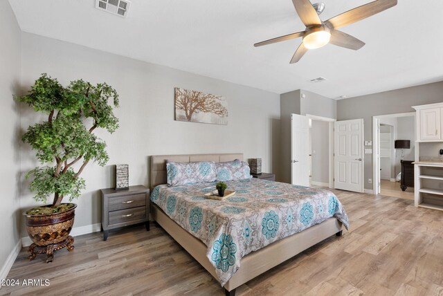 bedroom with ceiling fan, a fireplace, access to outside, and light wood-type flooring