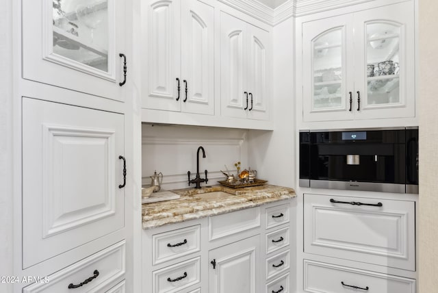 kitchen with light stone countertops, sink, and white cabinetry