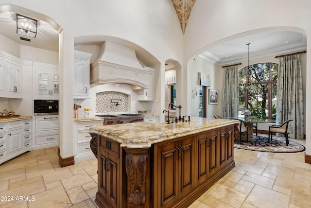 kitchen with backsplash, custom exhaust hood, white cabinetry, and light tile flooring