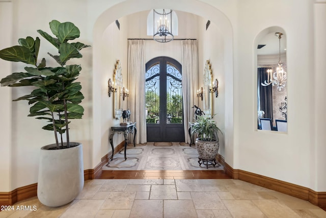 tiled foyer featuring french doors and an inviting chandelier