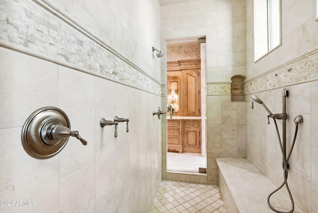 bathroom featuring a tile shower, tile floors, and tile walls