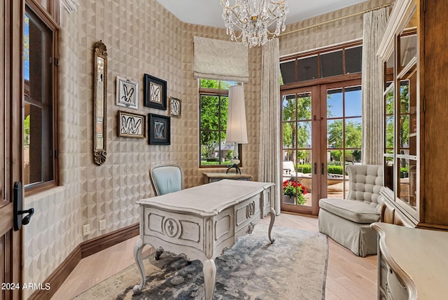 home office with a healthy amount of sunlight, a chandelier, light hardwood / wood-style floors, and french doors