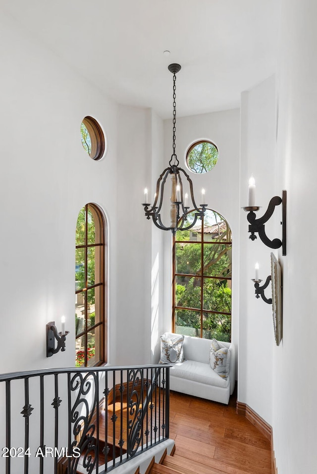 corridor with a towering ceiling, a chandelier, and wood-type flooring