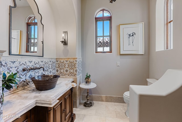 bathroom with tile flooring, tasteful backsplash, vanity, and toilet