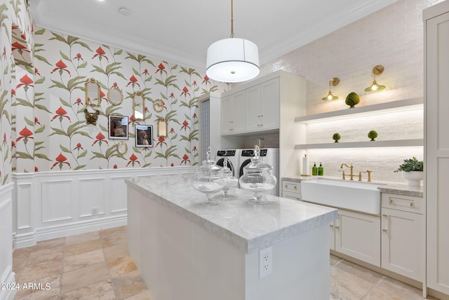 kitchen with light stone counters, crown molding, a center island, sink, and light tile floors