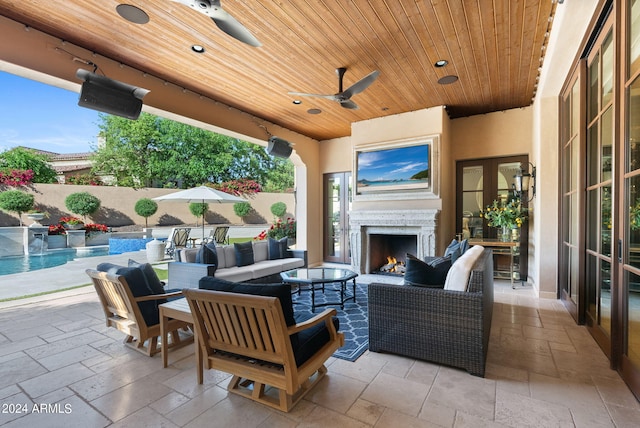 view of patio / terrace featuring ceiling fan, a fenced in pool, and an outdoor living space with a fireplace