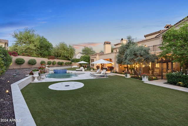 yard at dusk with a fenced in pool and a patio