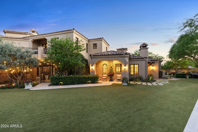 back house at dusk with a lawn