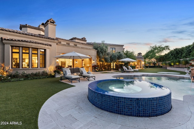 pool at dusk featuring a patio, an outdoor hangout area, pool water feature, and a lawn