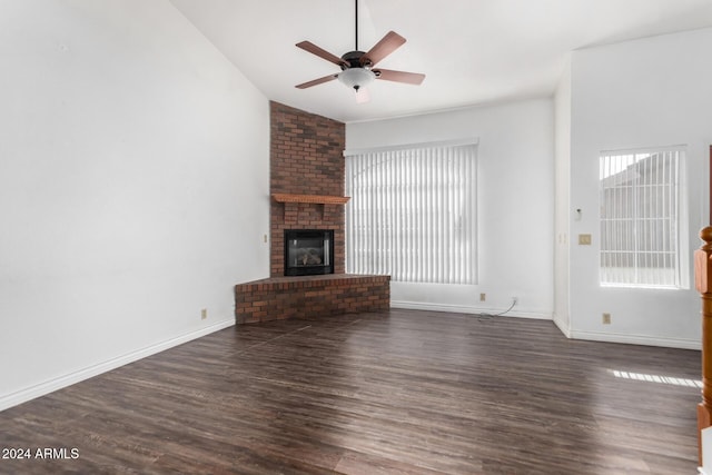 unfurnished living room featuring ceiling fan, dark wood-type flooring, and a brick fireplace