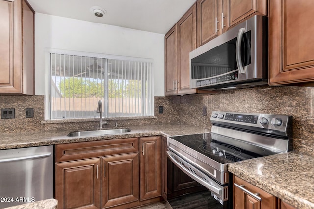 kitchen with backsplash, dark stone countertops, sink, and stainless steel appliances