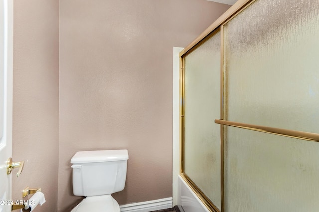 bathroom featuring toilet and bath / shower combo with glass door