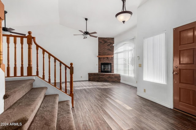 foyer with a fireplace, ceiling fan, hardwood / wood-style floors, and high vaulted ceiling