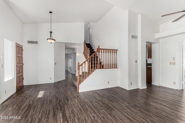 unfurnished living room featuring ceiling fan, a high ceiling, and dark hardwood / wood-style floors