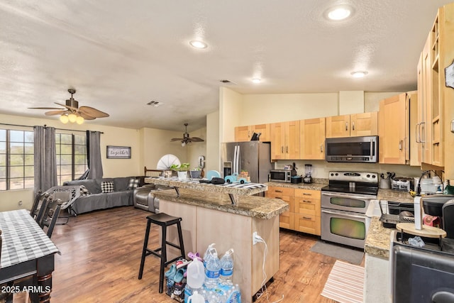 7259 E Glencove St, Mesa, AZ 85207 - kitchen with stainless steel appliances, light brown cabinets, ceiling fan, lofted ceiling, and a kitchen bar