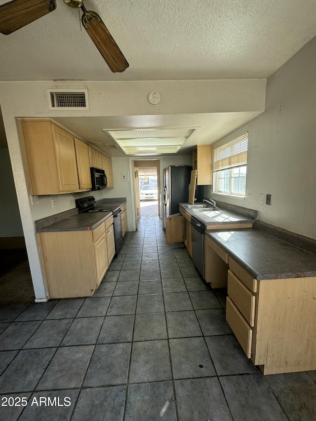 kitchen featuring visible vents, light brown cabinetry, black appliances, dark countertops, and a wealth of natural light