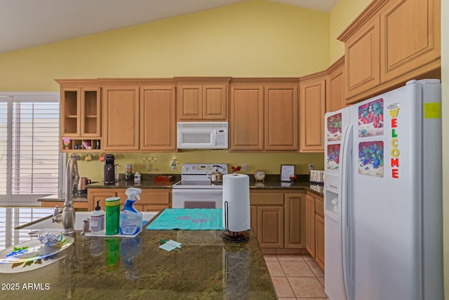 kitchen with lofted ceiling, white appliances, light tile patterned flooring, and dark stone countertops