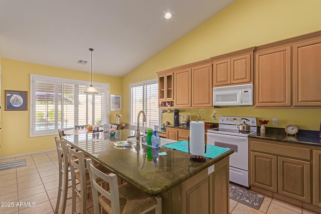 kitchen featuring brown cabinetry, white appliances, a breakfast bar area, and a center island with sink