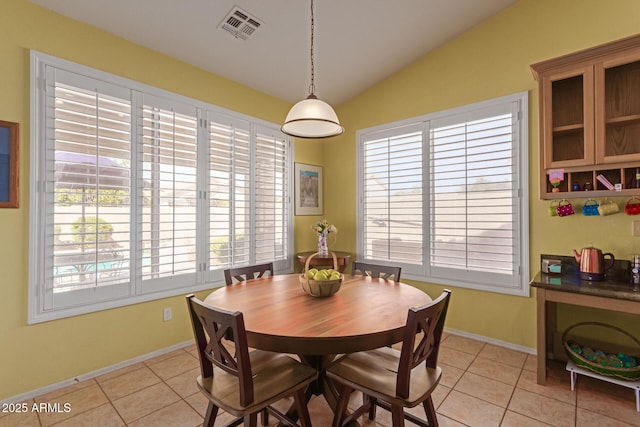 dining room featuring light tile patterned floors, baseboards, visible vents, and vaulted ceiling