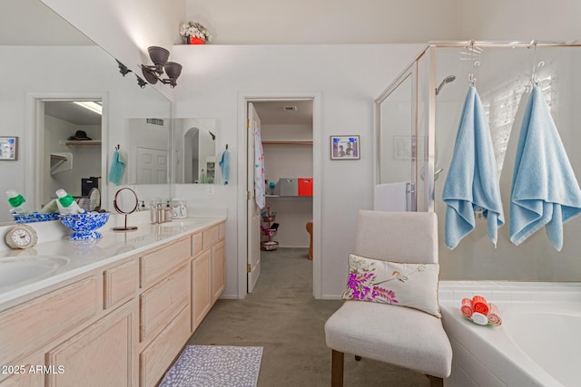 bathroom with double vanity, a shower stall, and a spacious closet