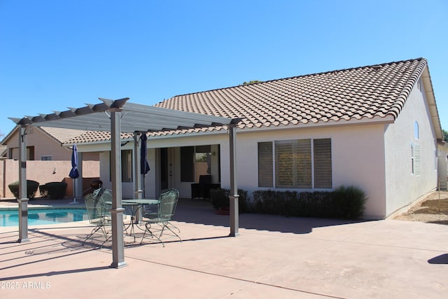 rear view of property featuring a fenced in pool, a patio, a tiled roof, a pergola, and stucco siding