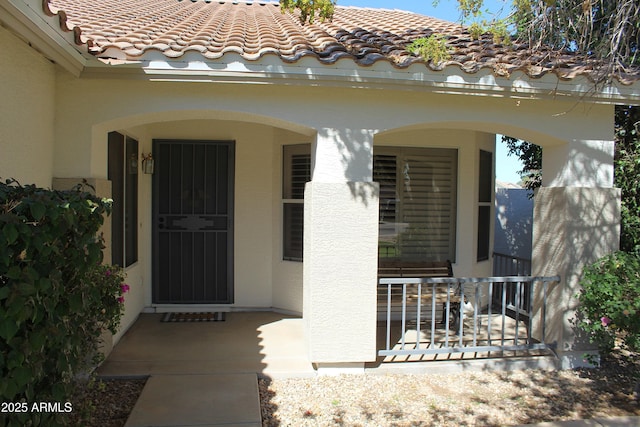 view of exterior entry featuring a tile roof and stucco siding