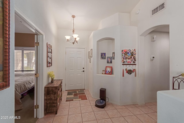 entrance foyer with light tile patterned floors, lofted ceiling, visible vents, and a notable chandelier