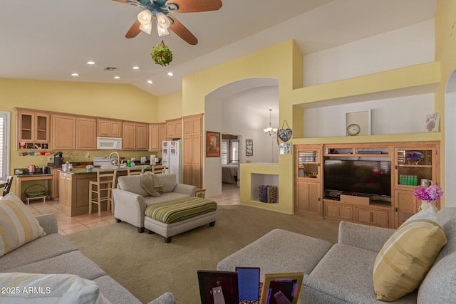 living area with light tile patterned floors, arched walkways, ceiling fan with notable chandelier, high vaulted ceiling, and recessed lighting