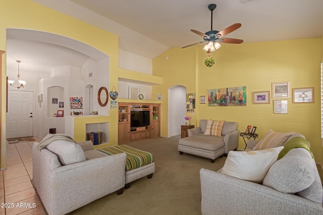 living room featuring light tile patterned floors, arched walkways, built in shelves, high vaulted ceiling, and ceiling fan with notable chandelier