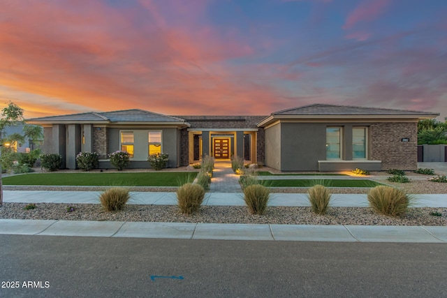 prairie-style home featuring stucco siding, roof mounted solar panels, a lawn, and french doors