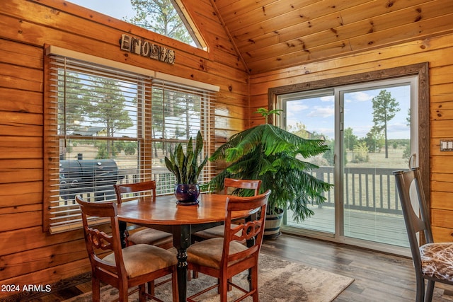 dining area featuring lofted ceiling, wooden walls, wood ceiling, and dark hardwood / wood-style floors