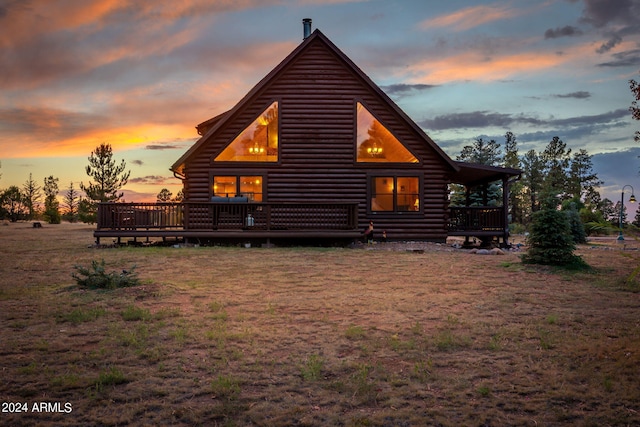 property exterior at dusk with a deck and a yard