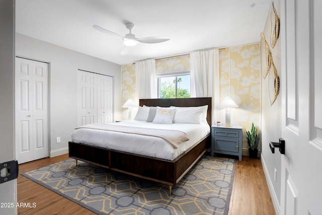 8001 E Voltaire Ave, Scottsdale, AZ 85260 - bedroom with wallpapered walls, two closets, wood finished floors, and a ceiling fan