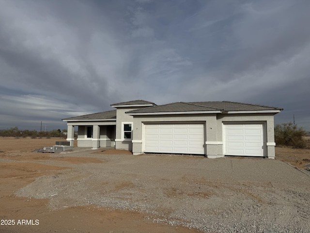 prairie-style home featuring a garage, driveway, and stucco siding