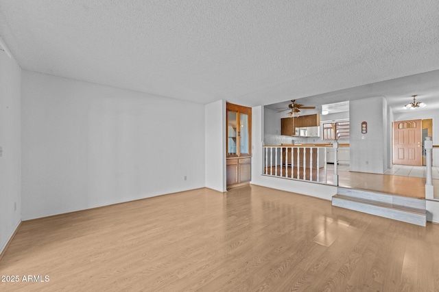 unfurnished living room featuring ceiling fan, a textured ceiling, and light wood-type flooring