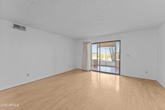 spare room with light hardwood / wood-style floors and a textured ceiling