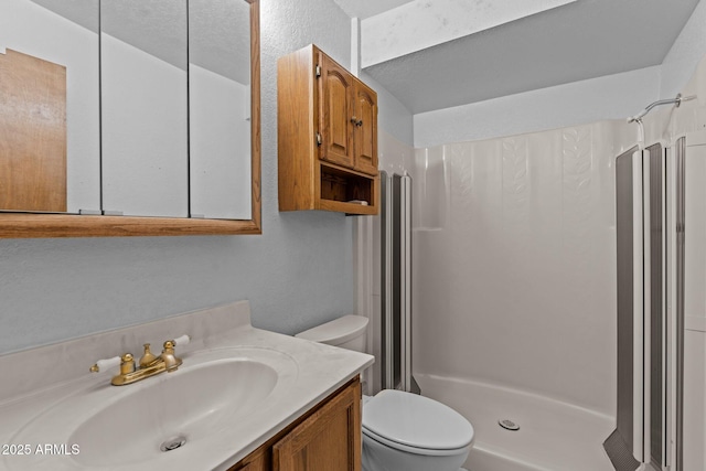 bathroom with vanity, toilet, and a shower