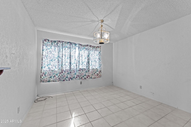 empty room featuring a notable chandelier and a textured ceiling