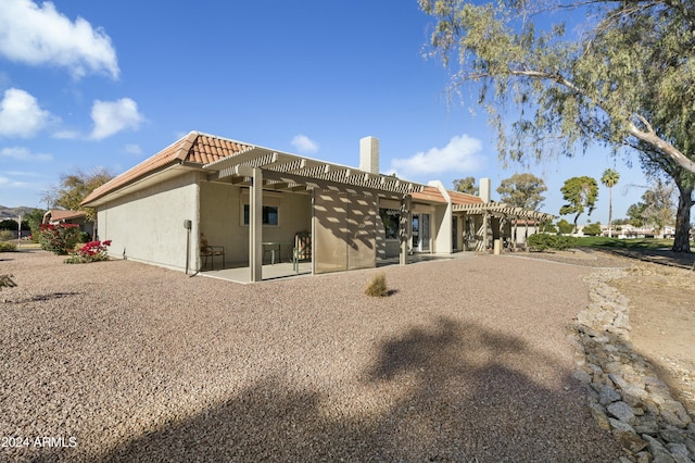 rear view of property featuring a pergola and a patio area