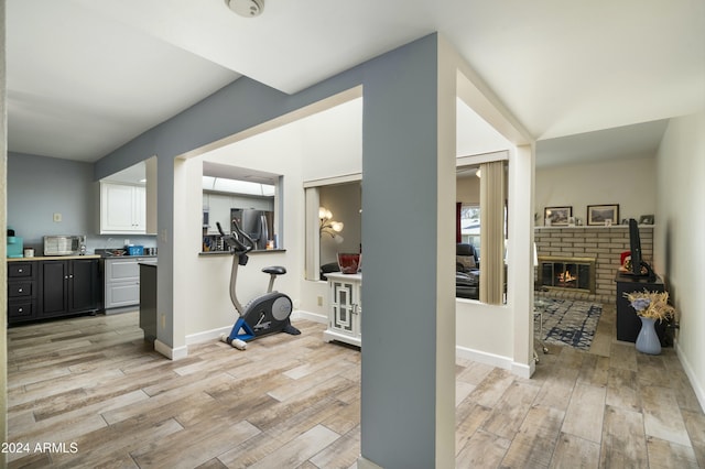 workout area with a fireplace and light hardwood / wood-style flooring