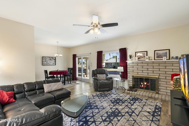 living room featuring a fireplace, hardwood / wood-style floors, and ceiling fan with notable chandelier