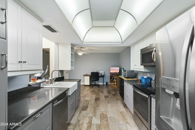 kitchen with appliances with stainless steel finishes, ceiling fan, sink, light hardwood / wood-style flooring, and white cabinets