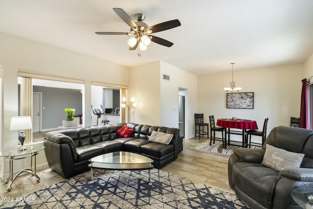 living room with light hardwood / wood-style floors and ceiling fan with notable chandelier